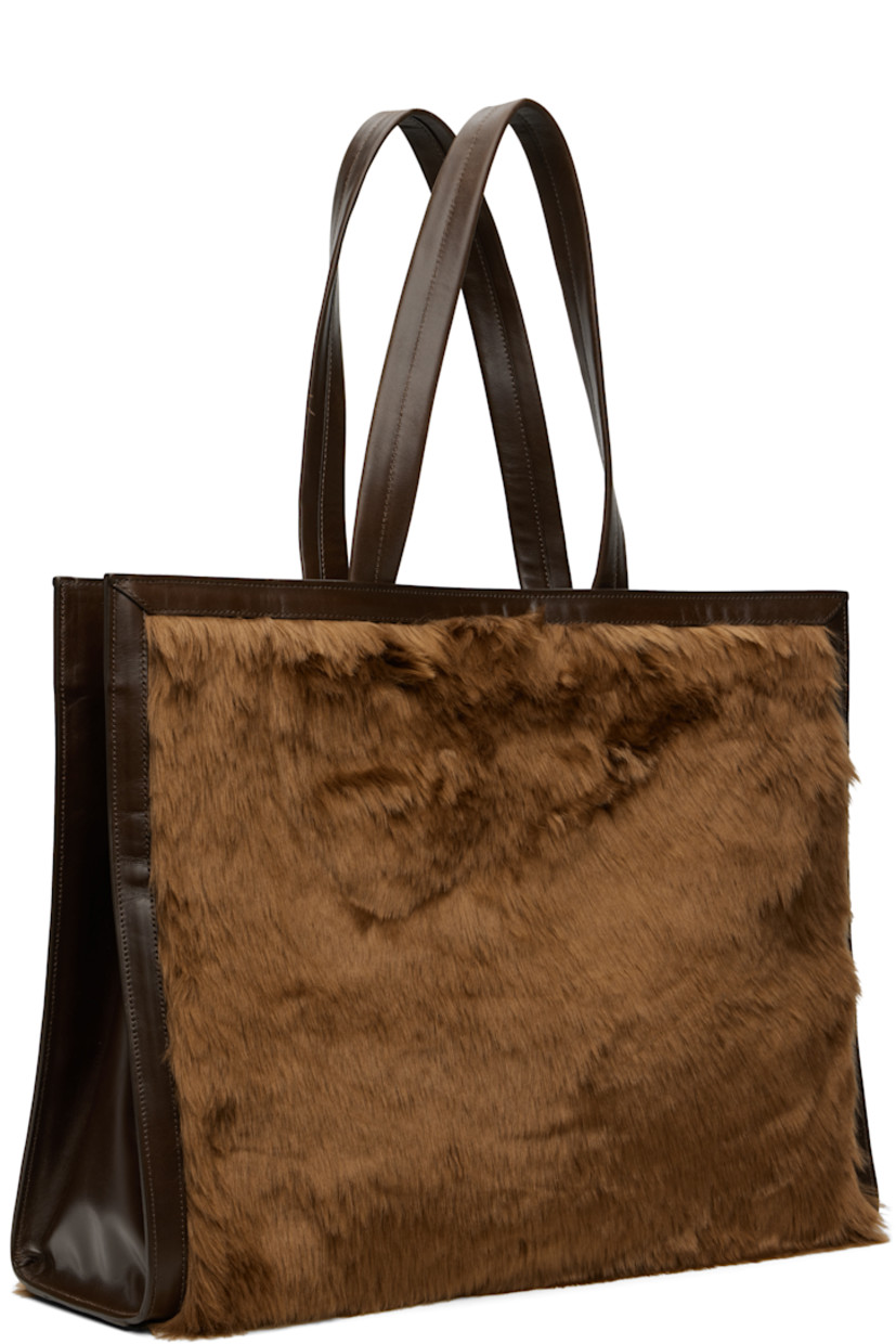 Faux-fur and buffed faux-leather tote.

· Leather shoulder straps
· Press-stud tab fastening at throat
· Detachable pouch with press-stud fastening at interior
· Pouch features four card slots and one note slot
· Alternate press-stud fastening at face
· Patch pocket at interior
· Twill lining
· H14" x W18" x D6"

Supplier color: Brown