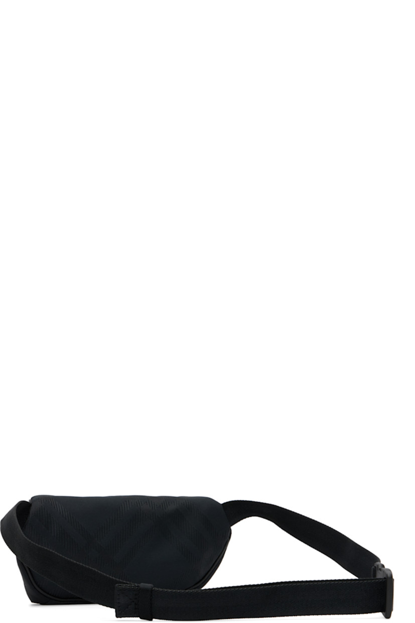 Nylon canvas belt bag. 

· Woven check pattern throughout 
· Adjustable crossbody strap
· Zip pocket with logo plaque at face
· Zip closure
· Poplin lining
· H6" x W10" x D4.5"

Supplier color: Black