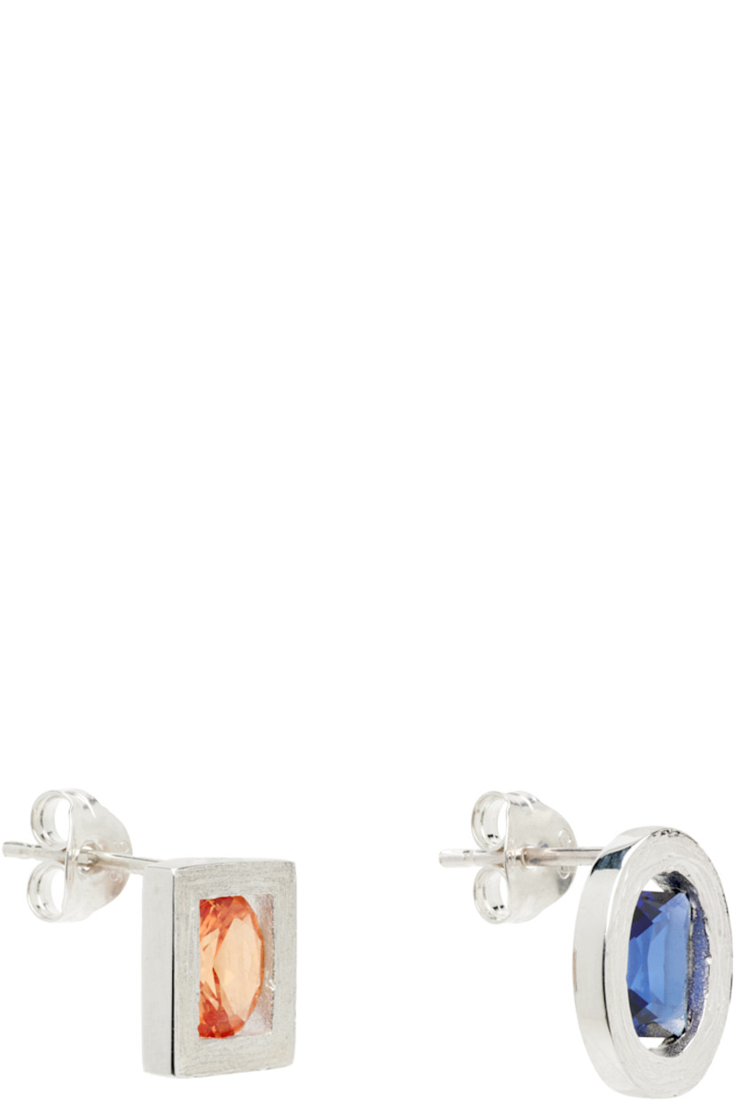 Pair of mismatched handcrafted stud earrings in textured sterling silver. 

· Bezel-set blue and orange lab-grown sapphires 
· Full hallmarking at back face 
· Post-stud fastening 
· H0.5" x W0.25"

Supplier color: Silver