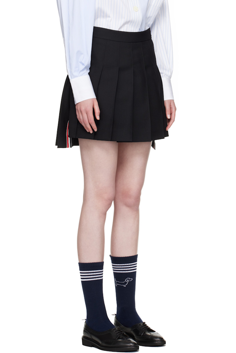 Wool fresco miniskirt. Knife pleats throughout.

· Adjustable button tab at waistband
· Tricolor grosgrain trim at vented droptail hem
· Concealed zip closure at side
· Tricolor grosgrain flag at back waistband
· Full sateen lining

Supplier color: Black