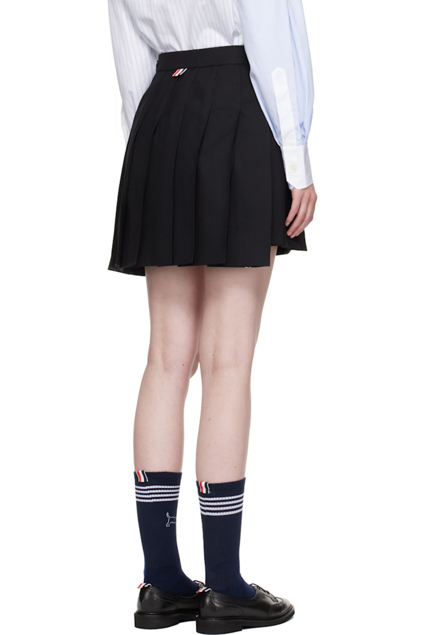 Wool fresco miniskirt. Knife pleats throughout.

· Adjustable button tab at waistband
· Tricolor grosgrain trim at vented droptail hem
· Concealed zip closure at side
· Tricolor grosgrain flag at back waistband
· Full sateen lining

Supplier color: Black