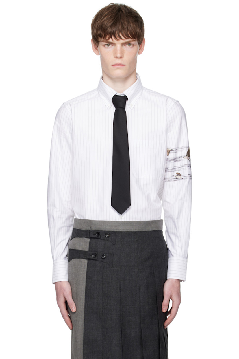 Cotton oxford cloth shirt.

· Pinstripes throughout
· Spread collar
· Button closure
· Patch pocket at chest
· Logo patch at front hem
· Shirttail hem
· Graphic embroidered at sleeve
· Buttoned barrel cuffs
· Tricolor grosgrain flag at back collar
· Locker loop and pleats at back yoke

Supplier color: Med grey