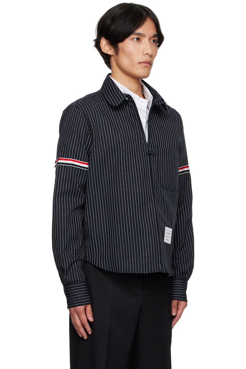 Virgin wool-blend canvas shirt. 

· Pinstripes throughout 
· Button tab at spread collar 
· Zip closure
· Patch pocket at front 
· Shirttail hem 
· Tricolor grosgrain appliqué at sleeve
· Buttoned barrel cuffs
· Tricolor grosgrain flag at back collar 
· Locker loop and twin pleats at back yoke 

Supplier color: Navy