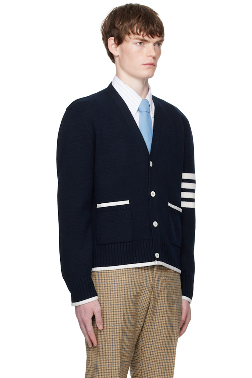 Knit virgin wool cardigan.

· Grosgrain trim throughout
· Rib-knit Y-neck, hem, and cuffs
· Button closure
· Patch pockets at waist
· Button vent at side seams and cuffs
· Stripes at sleeve
· Tricolor grosgrain flag at back collar

Supplier color: Navy