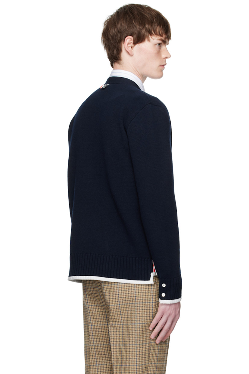 Knit virgin wool cardigan.

· Grosgrain trim throughout
· Rib-knit Y-neck, hem, and cuffs
· Button closure
· Patch pockets at waist
· Button vent at side seams and cuffs
· Stripes at sleeve
· Tricolor grosgrain flag at back collar

Supplier color: Navy