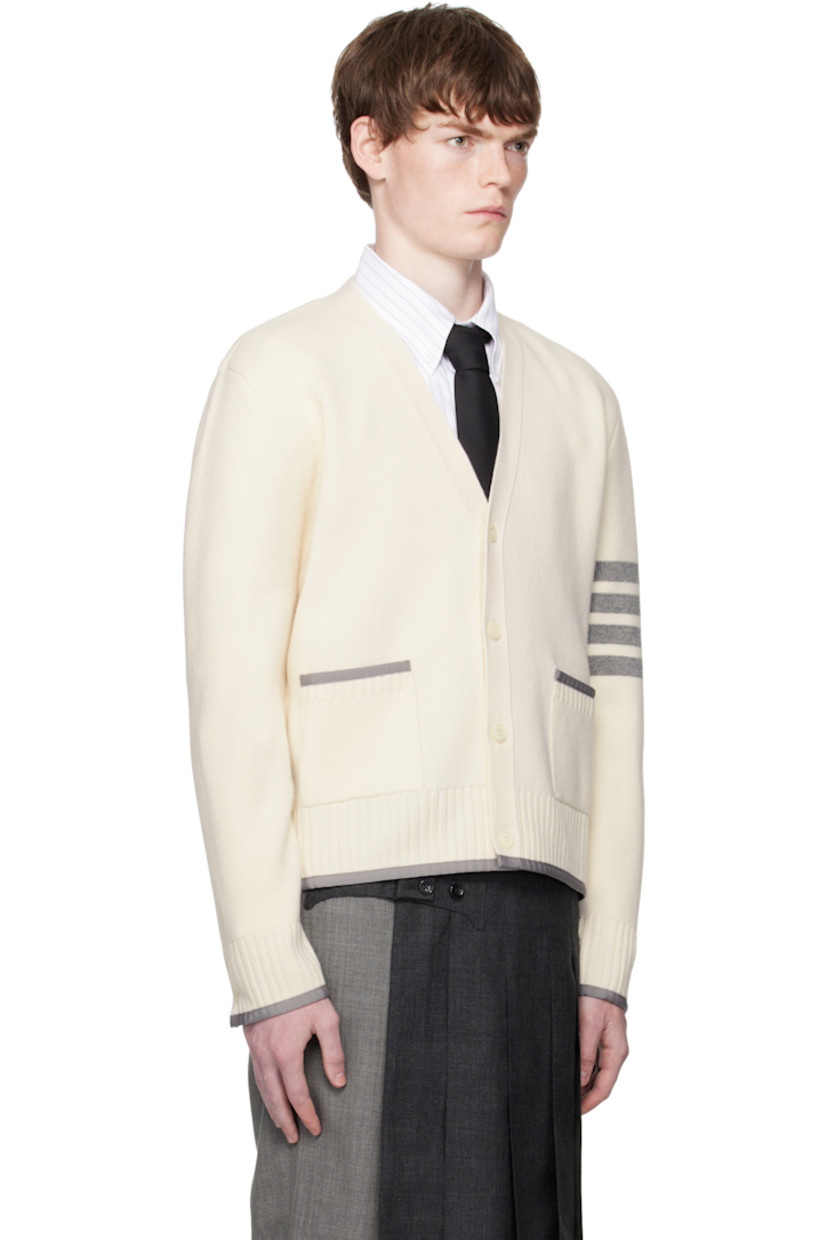 Knit virgin wool cardigan.

· Grosgrain trim throughout
· Rib-knit Y-neck, hem, and cuffs
· Button closure
· Patch pockets at waist
· Button vent at side seams and cuffs
· Stripes at sleeve
· Tricolor grosgrain flag at back collar

Supplier color: White