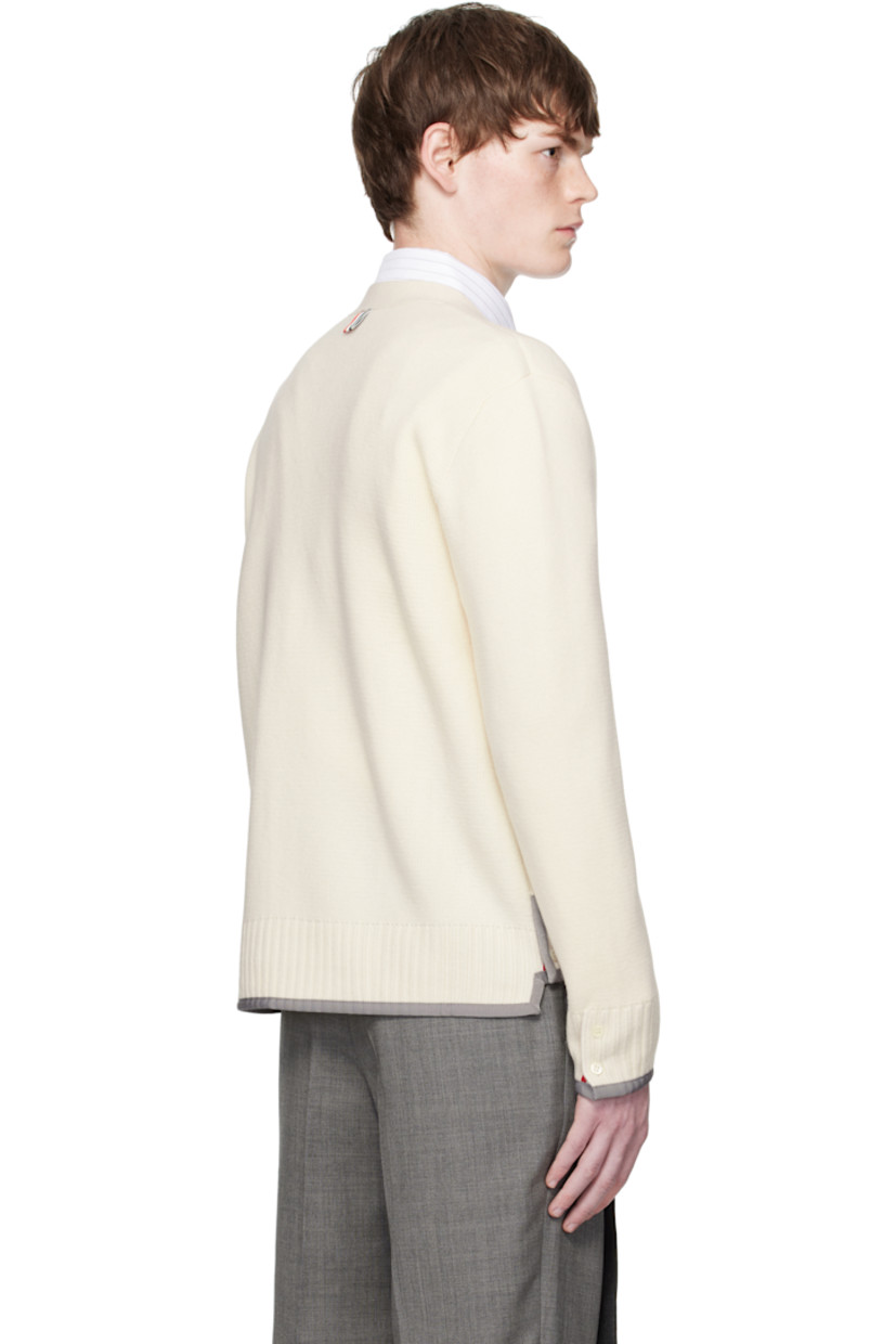 Knit virgin wool cardigan.

· Grosgrain trim throughout
· Rib-knit Y-neck, hem, and cuffs
· Button closure
· Patch pockets at waist
· Button vent at side seams and cuffs
· Stripes at sleeve
· Tricolor grosgrain flag at back collar

Supplier color: White