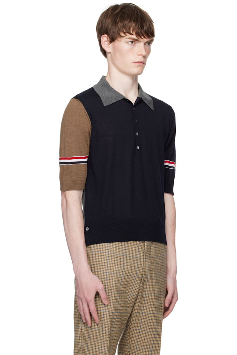 Knit virgin wool polo.

· Rib-knit spread collar, hem, and cuffs
· Five-button placket
· Button vent at side seams
· Stripes at sleeves
· Tricolor grosgrain flag at back collar

Supplier color: Navy/Grey/Brown