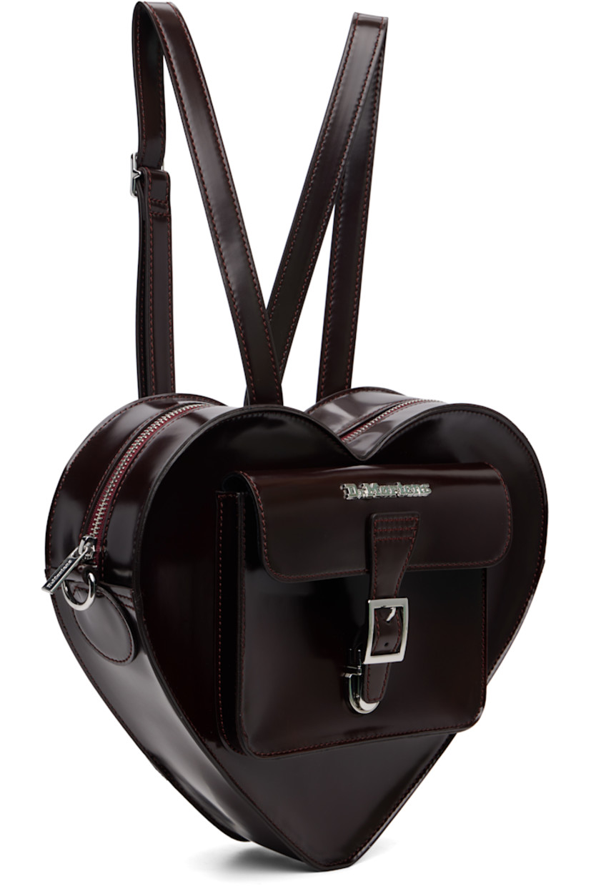 Heart-shaped buffed faux-leather backpack.

· Adjustable and detachable sliding shoulder strap
· Strap converts to crossbody
· Logo hardware and flap pocket at face
· Card slot at back face
· Twill lining
· H9.5" x W12" x D3"

Supplier color: Cherry red arcadia/Oxford rub off