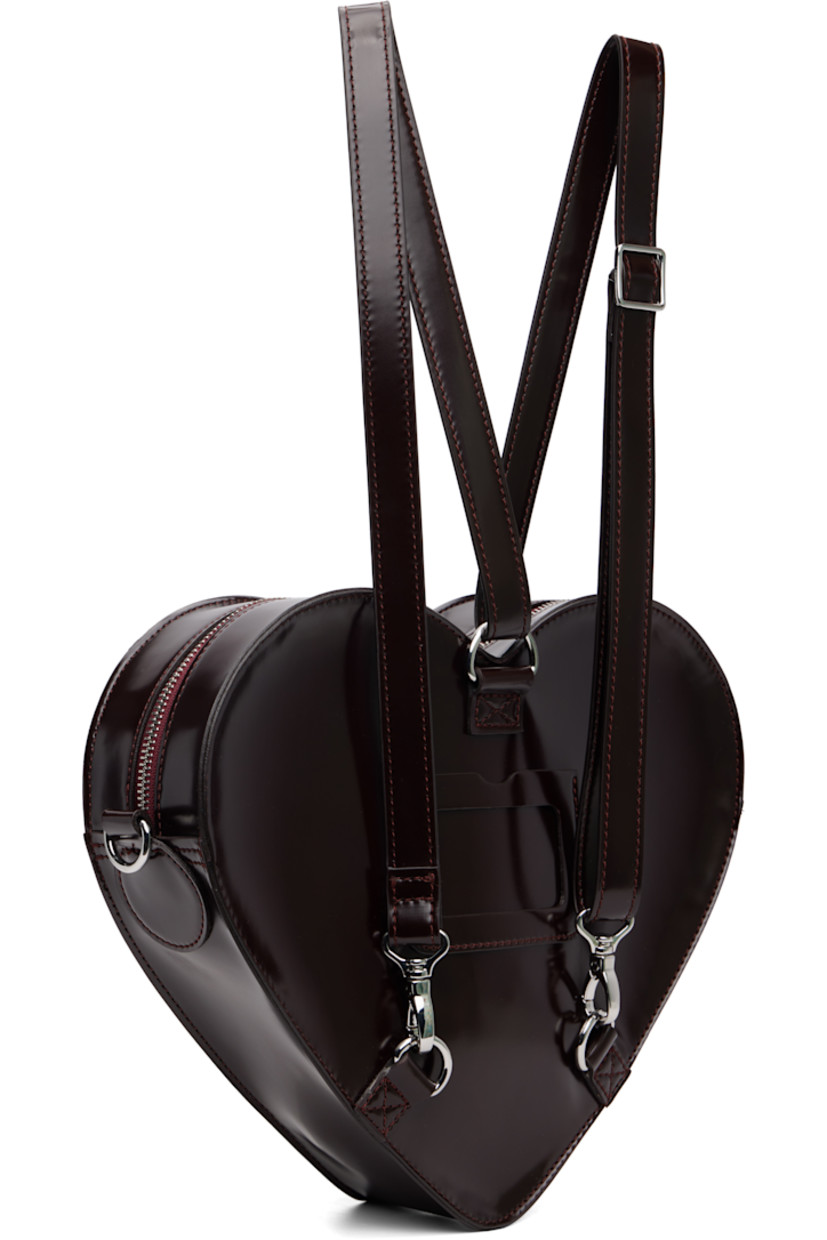 Heart-shaped buffed faux-leather backpack.

· Adjustable and detachable sliding shoulder strap
· Strap converts to crossbody
· Logo hardware and flap pocket at face
· Card slot at back face
· Twill lining
· H9.5" x W12" x D3"

Supplier color: Cherry red arcadia/Oxford rub off
