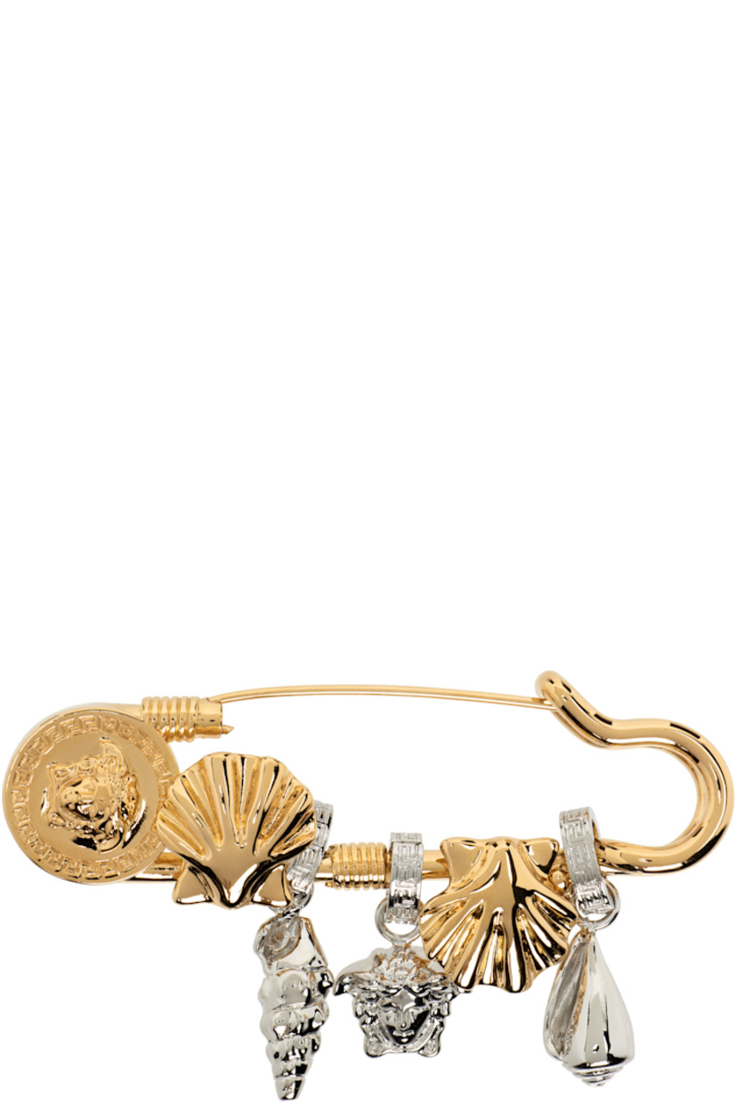 Brooch in gold- and silver-tone. 

· Graphic and Medusa charms at face
· Safety-pin fastening 
· H0.75" x W3"

Part of the La Vacanza collection.

Supplier color: Versace gold/Palladium