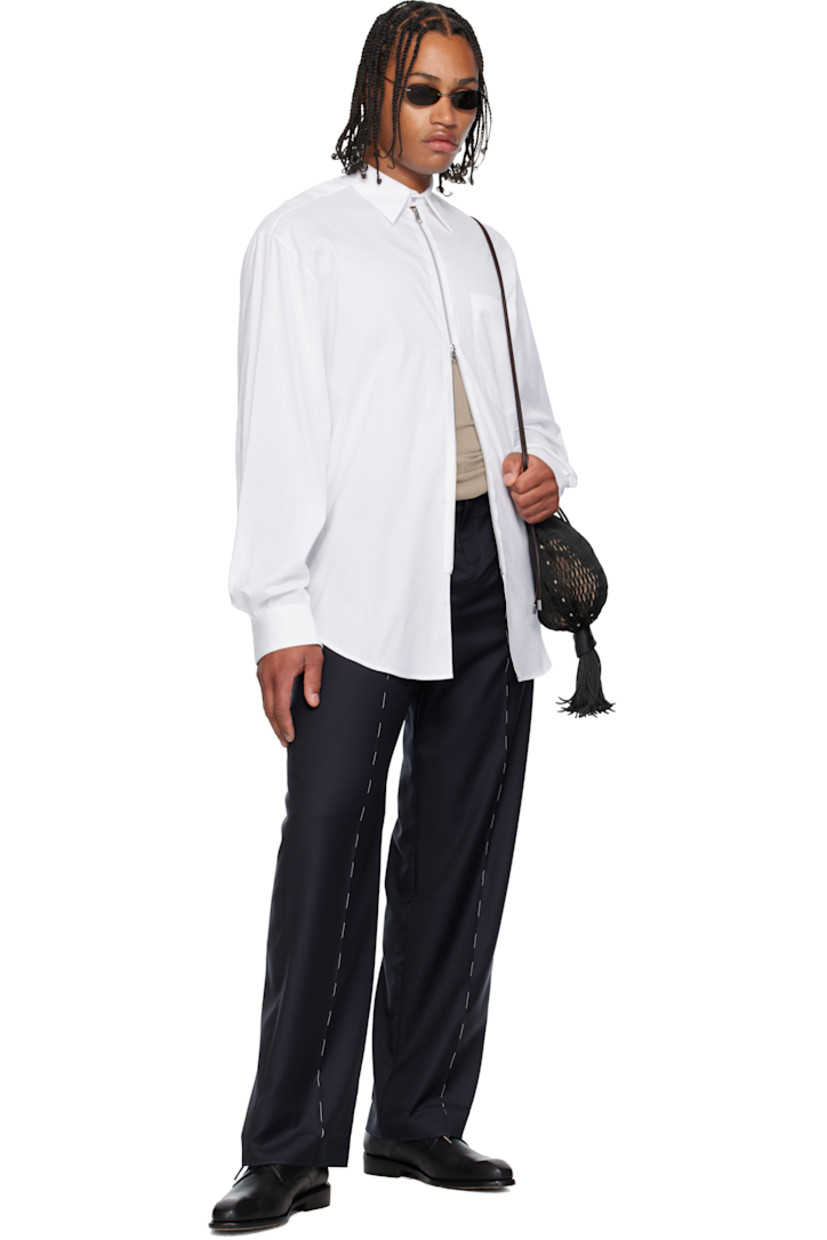 Cotton oxford cloth shirt. 

· Spread collar 
· Two-way zip closure
· Patch pocket at chest
· Shirttail hem 
· Pleats at buttoned barrel cuffs and back collar 

Supplier color: White
