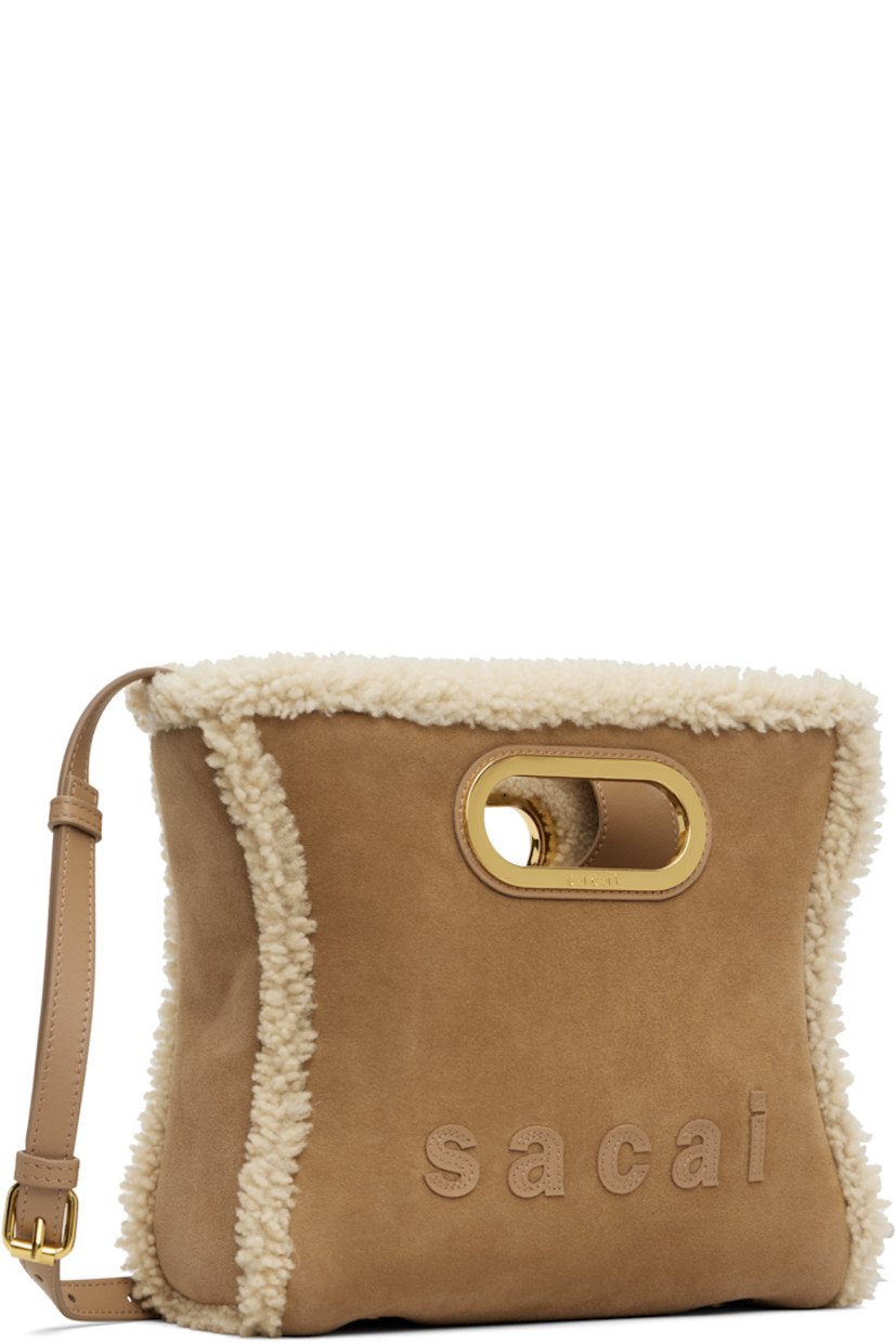 Shearling shoulder bag.

· Integrated carry handles
· Adjustable and detachable shoulder strap
· Logo appliqués at face and back
· Bumper studs at base
· Open throat
· Card slot at interior 
· H8.5" x W9.5" x D3"

Supplier color: Camel