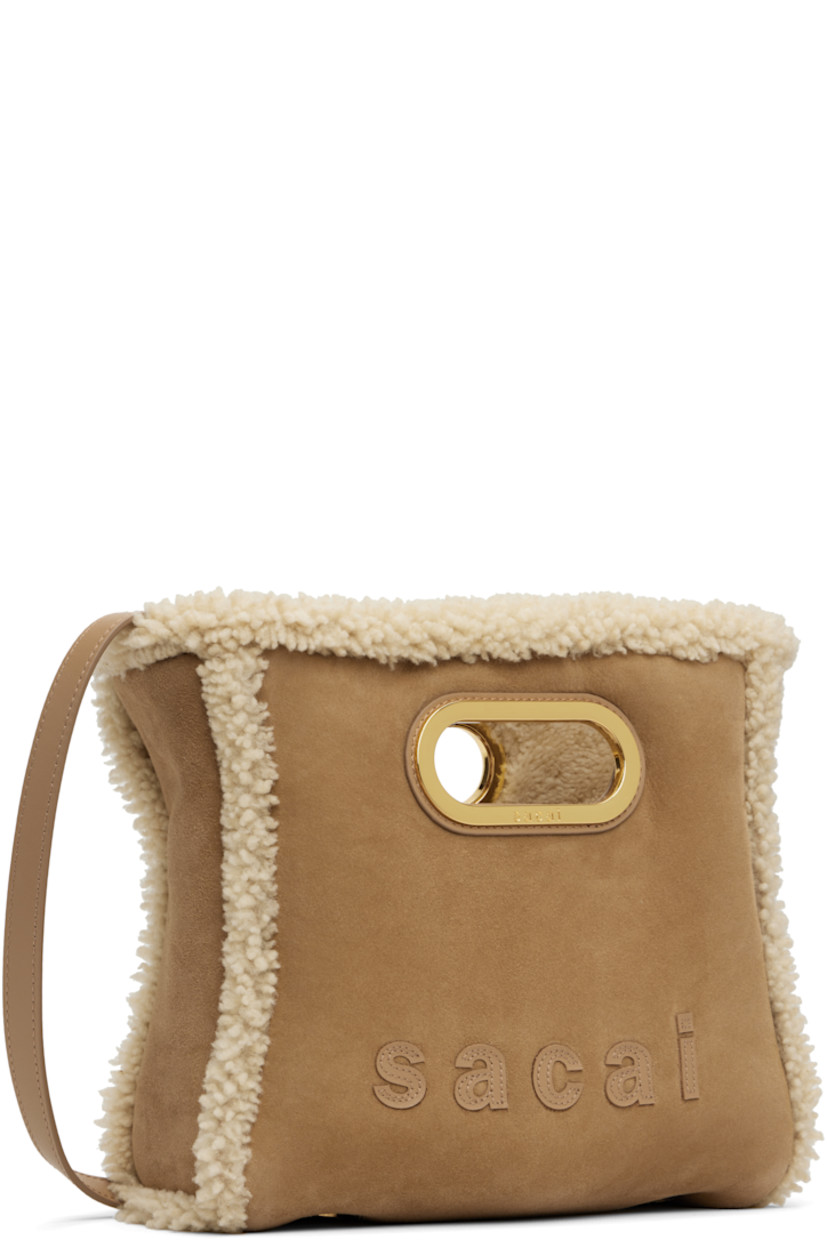 Shearling shoulder bag.

· Integrated carry handles
· Adjustable and detachable shoulder strap
· Logo appliqués at face and back
· Bumper studs at base
· Open throat
· Card slot at interior 
· H8.5" x W9.5" x D3"

Supplier color: Camel