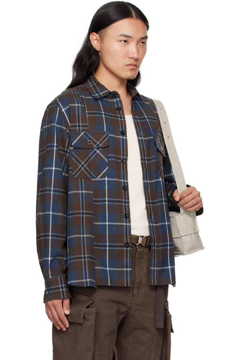 Cotton flannel shirt. 

· Check pattern throughout 
· Spread collar 
· Button closure
· Flap pockets at chest
· Shirttail hem
· Pleats at buttoned barrel cuffs
· Box pleat at back yoke

Supplier color: Brown/Blue