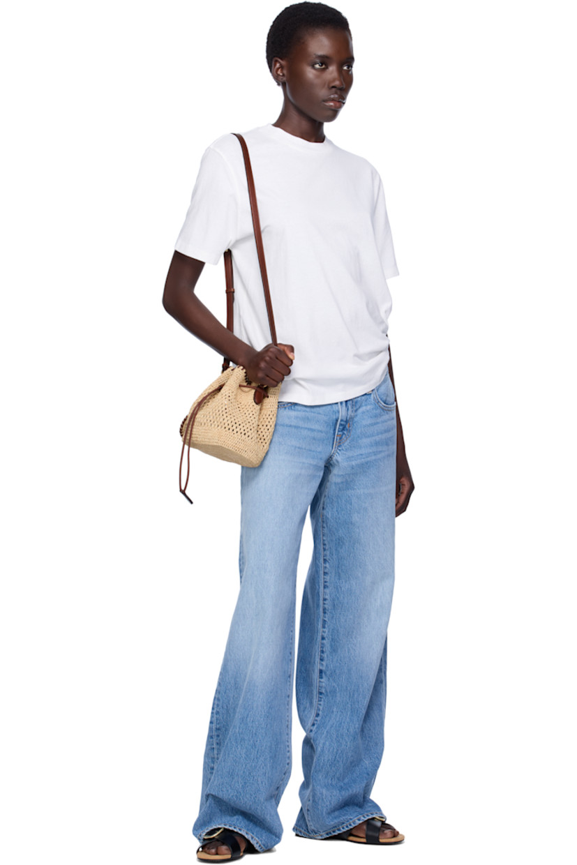 Handcrafted woven raffia tote in beige.

· GOTS-certified organic cotton whipstitching
· Adjustable crossbody strap
· Detachable charm with hand-embroidered logo at strap
· Drawstring closure
· Patch pocket at interior
· H7.5" x W7.5" x D5"

Made from cruelty-free, non-animal materials.

Supplier color: Natural