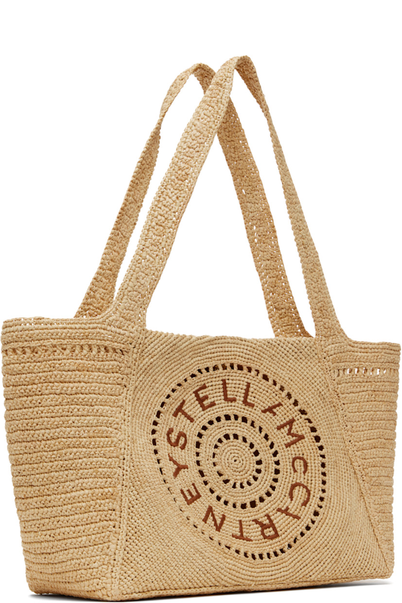 Handcrafted woven raffia tote in beige.

· Fixed shoulder straps
· Hand-embroidered logo at face
· Magnetic press-stud closure
· Patch pocket at interior
· H9" x W15.5" x D5"

Made from cruelty-free, non-animal materials.

Supplier color: Natural
