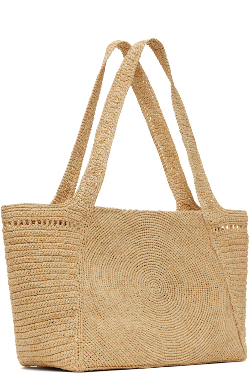 Handcrafted woven raffia tote in beige.

· Fixed shoulder straps
· Hand-embroidered logo at face
· Magnetic press-stud closure
· Patch pocket at interior
· H9" x W15.5" x D5"

Made from cruelty-free, non-animal materials.

Supplier color: Natural