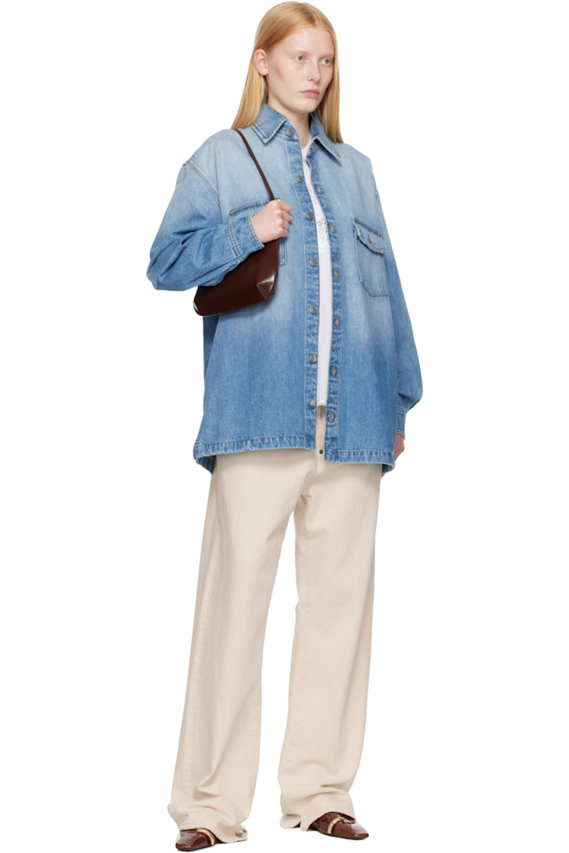 Non-stretch GOTS-certified organic cotton denim shirt. Fading throughout. 

· Spread collar
· Button closure
· Flap pockets at chest
· Shirttail hem
· Vented side seams
· Dropped shoulders
· Pleats at buttoned barrel cuffs
· Box pleat at back yoke
· Logo embroidered at back hem
· Logo-engraved silver-tone hardware
· Contrast stitching in tan

Made from cruelty-free, non-animal materials.

Supplier color: Mid vintage blue