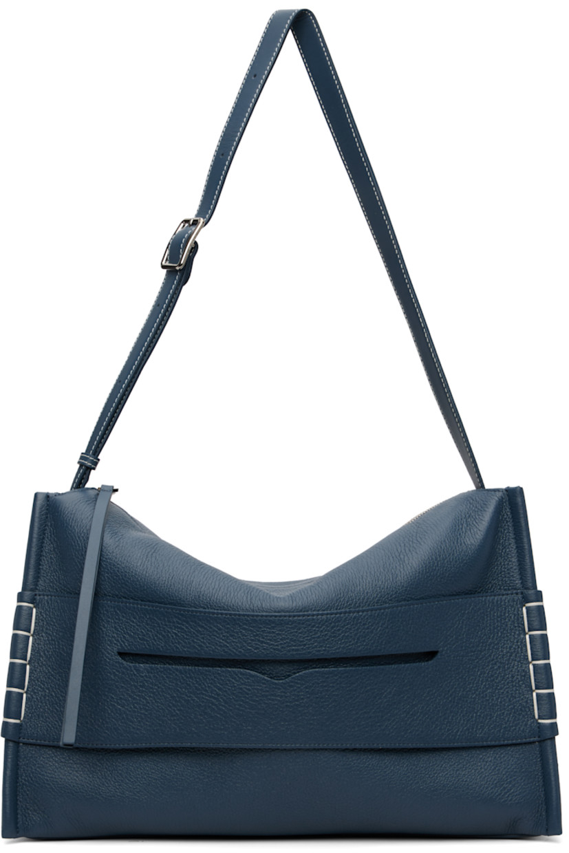 Pebble-grained calfskin shoulder bag. 

· Adjustable and detachable shoulder strap
· Strap with cutout and blanket stitching at face
· Logo embossed at back face
· Zip closure
· Patch pocket at interior 
· Suede lining 
· H11.5" x W16" x D6.5"

Supplier color: Denim blue