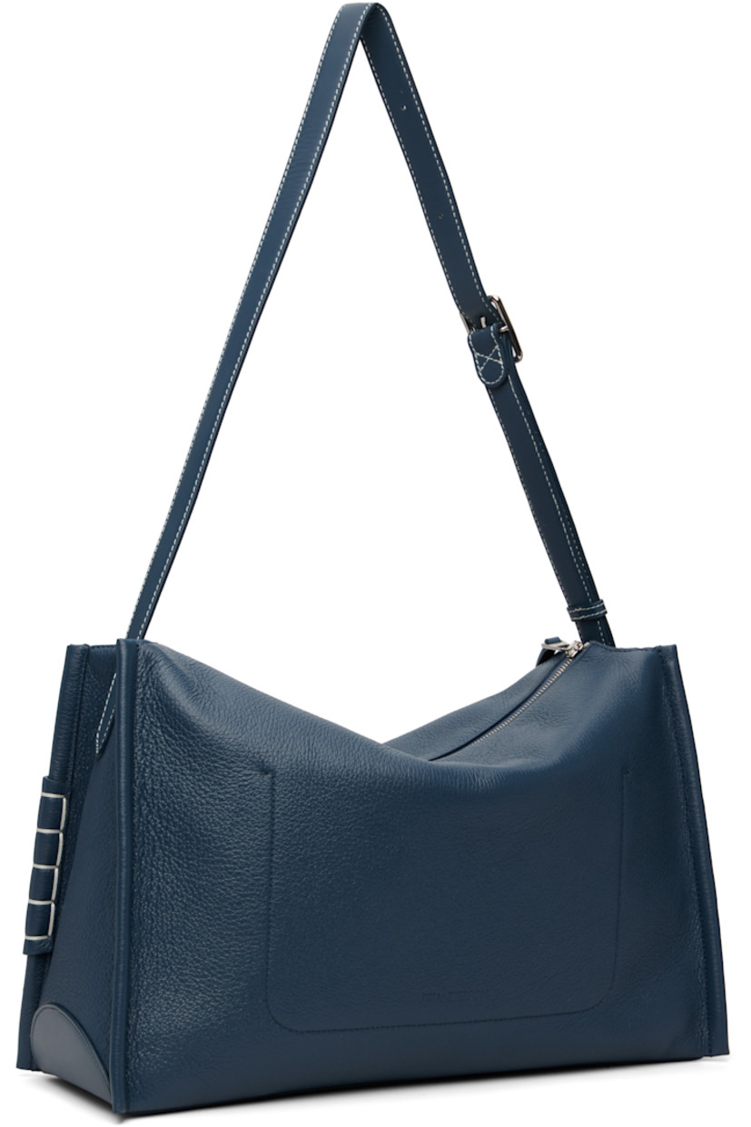 Pebble-grained calfskin shoulder bag. 

· Adjustable and detachable shoulder strap
· Strap with cutout and blanket stitching at face
· Logo embossed at back face
· Zip closure
· Patch pocket at interior 
· Suede lining 
· H11.5" x W16" x D6.5"

Supplier color: Denim blue
