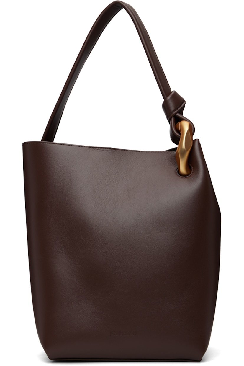 Buffed leather tote.

· Curb chain detailing at fixed shoulder strap
· Logo embossed at face
· Magnetic press-stud closure
· Patch pocket at interior
· Suede lining
· H12" x W12.5" x D7"

Supplier color: Deep walnut