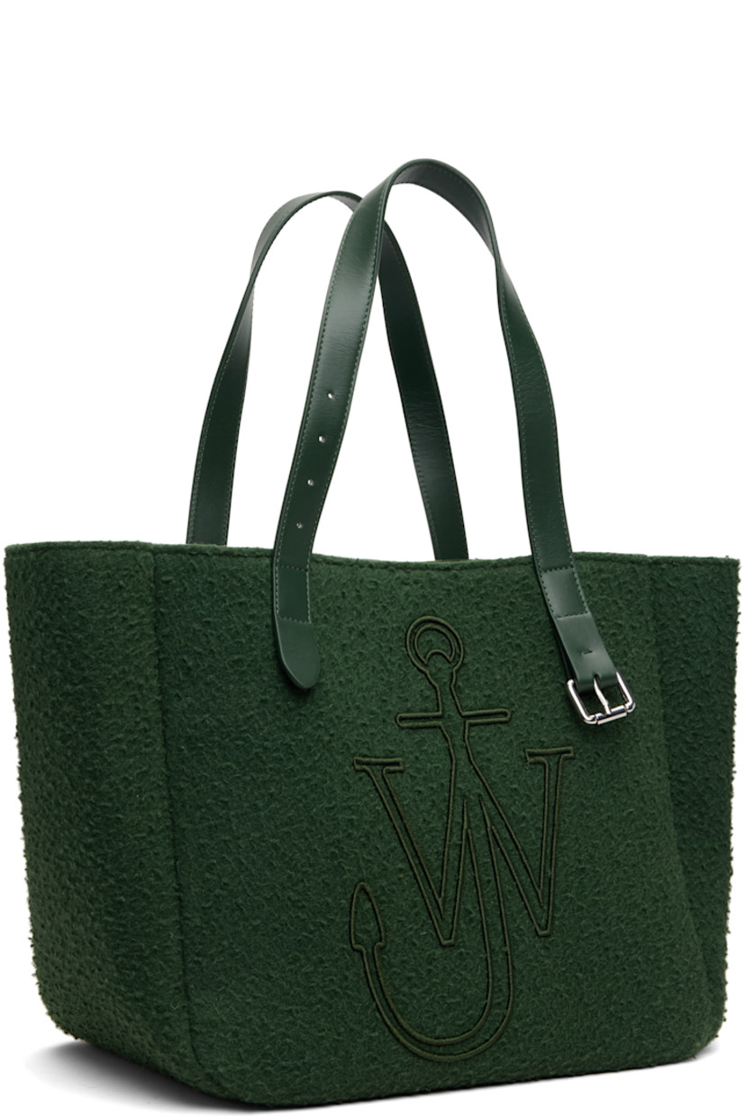 Melton tote.

· Fixed shoulder straps
· Pin-buckle hardware and embroidered logo at face
· Bumper pads at base
· Self-tie closure
· Patch pocket at interior
· H12" x W18" x D9"

Supplier color: Pine