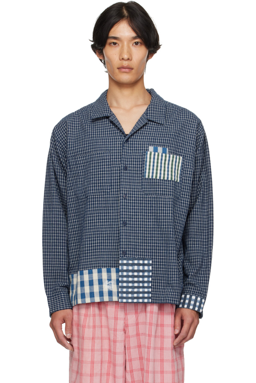 Hand-loomed plain-woven organic cotton shirt.

· Hand-block-printed and indigo-dyed check patterns
· Open spread collar
· Button closure
· Patch pocket at chest
· Embroidered logo at front hem
· Patchworking at hem and cuff
· Buttoned barrel cuffs
· Pleats at back yoke
· Corozo hardware

Supplier Color: Indigo Picnic Handloom