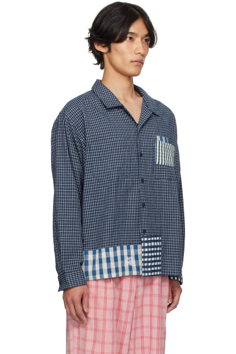 Hand-loomed plain-woven organic cotton shirt.

· Hand-block-printed and indigo-dyed check patterns
· Open spread collar
· Button closure
· Patch pocket at chest
· Embroidered logo at front hem
· Patchworking at hem and cuff
· Buttoned barrel cuffs
· Pleats at back yoke
· Corozo hardware

Supplier Color: Indigo Picnic Handloom