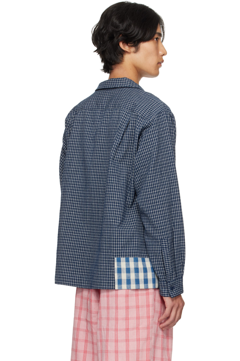 Hand-loomed plain-woven organic cotton shirt.

· Hand-block-printed and indigo-dyed check patterns
· Open spread collar
· Button closure
· Patch pocket at chest
· Embroidered logo at front hem
· Patchworking at hem and cuff
· Buttoned barrel cuffs
· Pleats at back yoke
· Corozo hardware

Supplier Color: Indigo Picnic Handloom