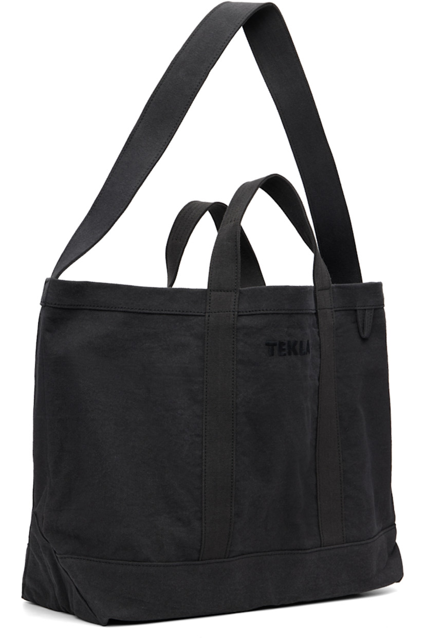 390 gsm organic cotton canvas tote.

· Garment-dyed
· Fixed carry handles and crossbody strap 
· Logo embroidered at face
· Patch pocket at back face
· Patch and zip pocket at interior
· H14" x W21" x D7"

Supplier color: Black sand/Washed black hue