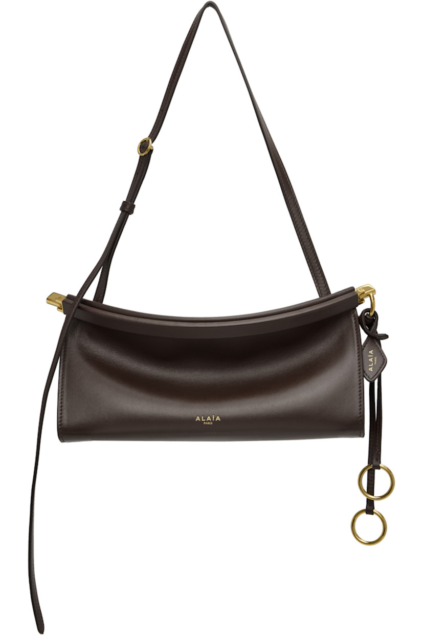 Buffed calfskin shoulder bag.

· Adjustable shoulder strap
· Logo stamp at face
· Detachable logo tag and O-rings at side
· Hinged closure
· Suede lining
· Logo-engraved gold-tone hardware
· H5" x W10" x D3"

Supplier color: Dark brown