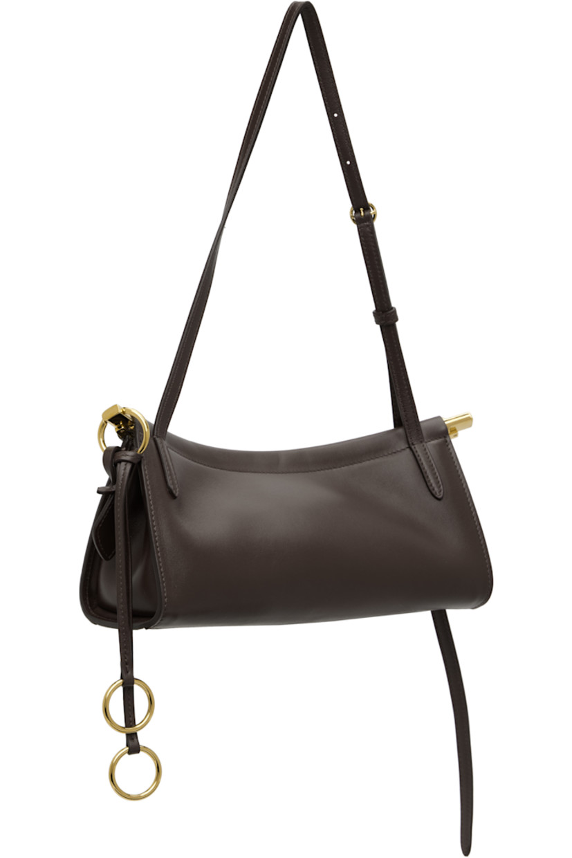 Buffed calfskin shoulder bag.

· Adjustable shoulder strap
· Logo stamp at face
· Detachable logo tag and O-rings at side
· Hinged closure
· Suede lining
· Logo-engraved gold-tone hardware
· H5" x W10" x D3"

Supplier color: Dark brown