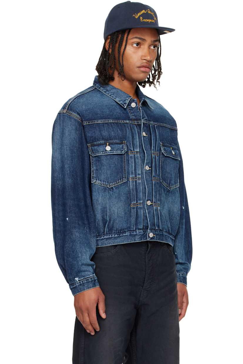Non-stretch denim jacket.

· Fading throughout
· Spread collar
· Button closure
· Tucks at front
· Flap pockets at chest
· Seam pockets
· Buttoned barrel cuffs
· Adjustable button tabs and logo patch at back hem
· Contrast stitching in tan

Supplier color: Navy