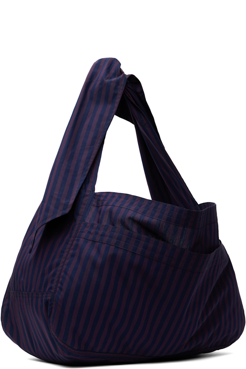 Cotton twill shoulder bag in purple and navy.

· Stripes throughout
· Fixed crossbody strap
· Patch compartment at face
· Open throat
· Unlined 
· H10" x W17" x D7.5"

Supplier color: Arcade