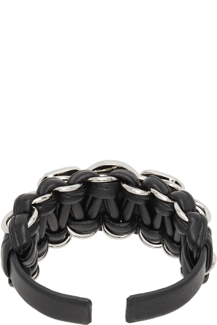 Open cuff braided leather bracelet in black. 

· Engraved graphic hardware at face
· O-rings at length
· Silver-tone hardware
· D2.75"

Supplier color: Black