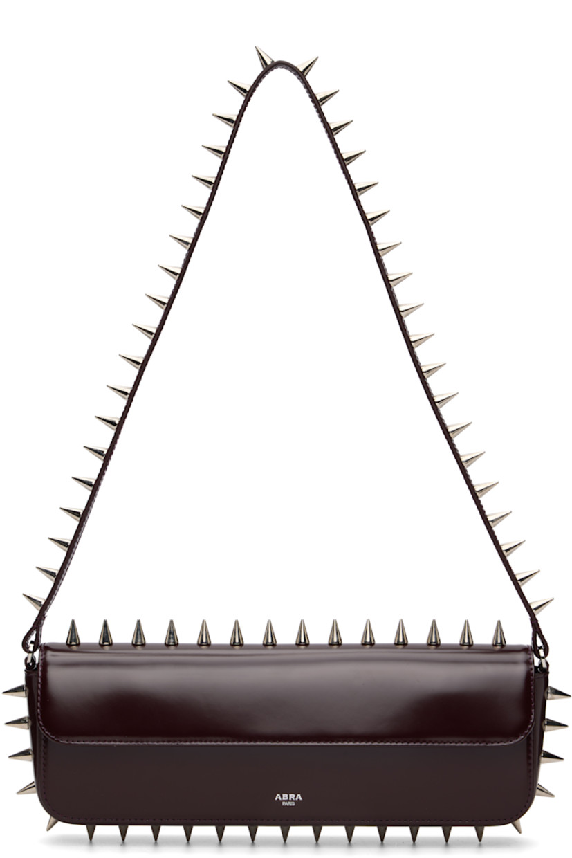 Structured polished leather shoulder bag.

· Studs throughout
· Fixed shoulder strap
· Silver-tone logo stamp at face
· Magnetic flap
· Patch pocket and D-ring at interior
· Silver-tone hardware
· H4" x W11.75" x D2"

Supplier color: Burgundy