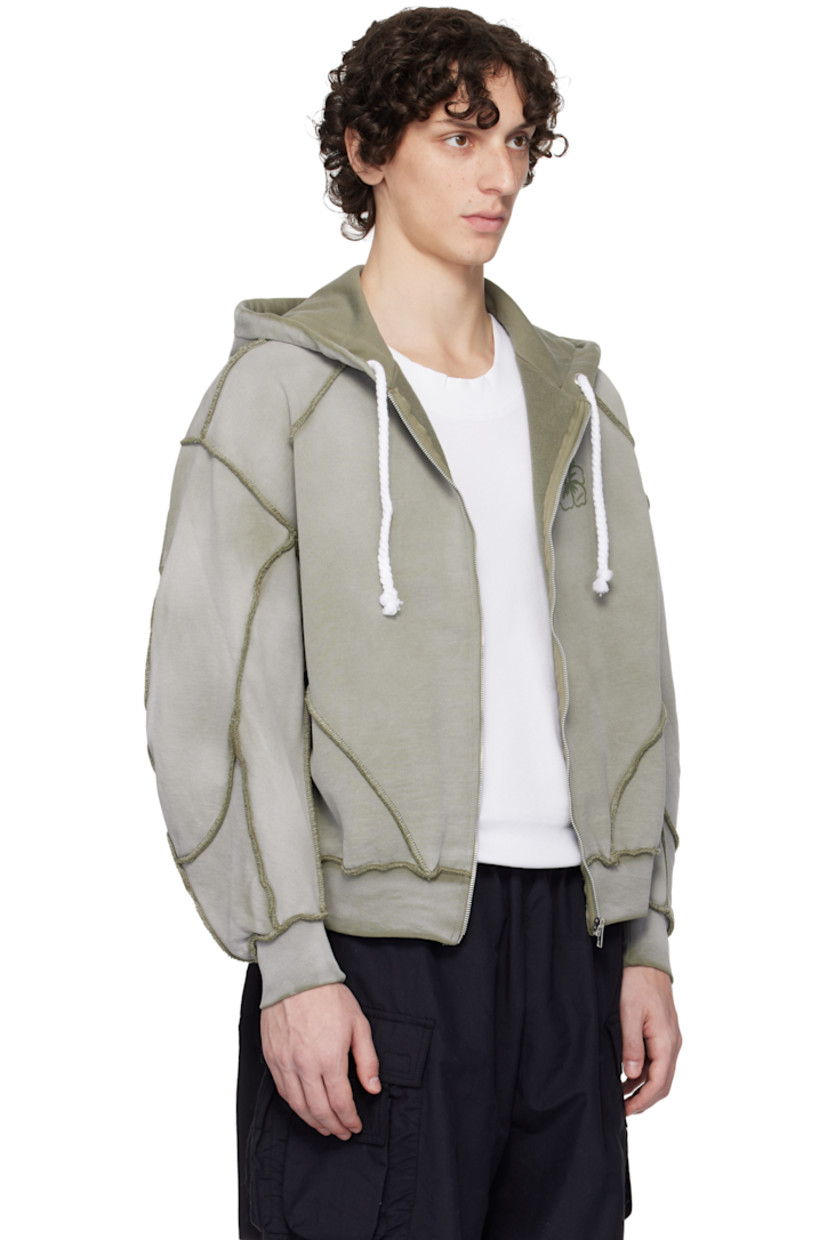 French terry hoodie. Exposed seams and fading throughout.

· Paneled construction
· Drawstring at hood
· Zip closure
· Logo graphic printed at chest
· Raglan sleeves
· Contrast stitching in khaki

Supplier color: Grey