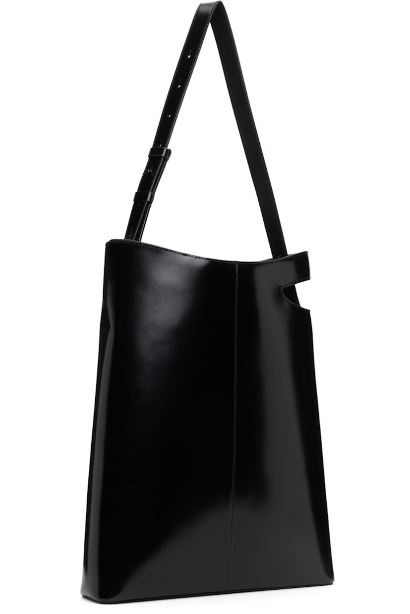 Polished leather tote.

· Adjustable shoulder strap
· Cutout and embossed logo at side
· Zip pocket at interior
· Faille lining
· H16" x W12 x D3"

Supplier color: Black