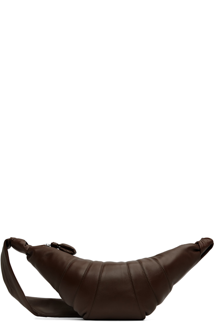Nappa lambskin shoulder bag.

· LWG Gold-certified lambskin
· Fixed knotted crossbody strap
· Padded pull-tab at zip closure
· Patch pocket at interior
· Cotton canvas lining
· H8.5" x W18" x D2"

Supplier color: Dark Chocolate