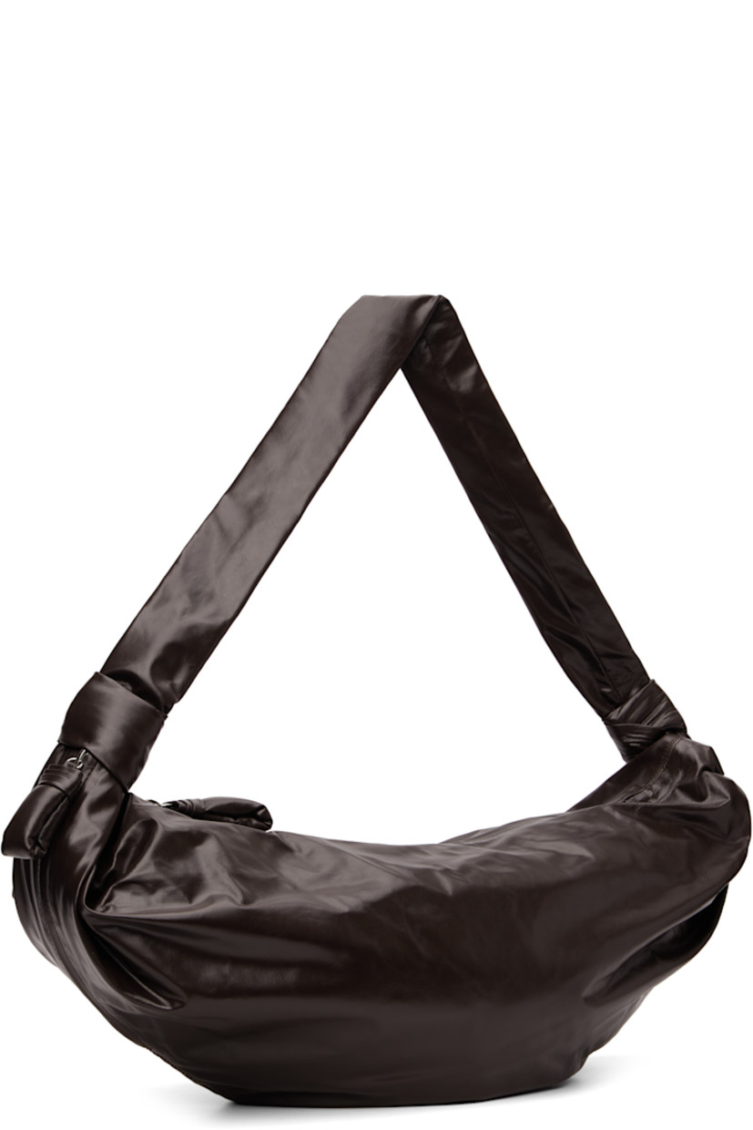 Coated leather shoulder bag.

· Knotted detailing at crossbody strap
· Zip pocket with padded pull-tab at side
· Padded pull-tab at zip closure
· Zip pocket at interior
· Cotton canvas lining
· H12.5" x W28" x D2.25"

Supplier color: Dark chocolate