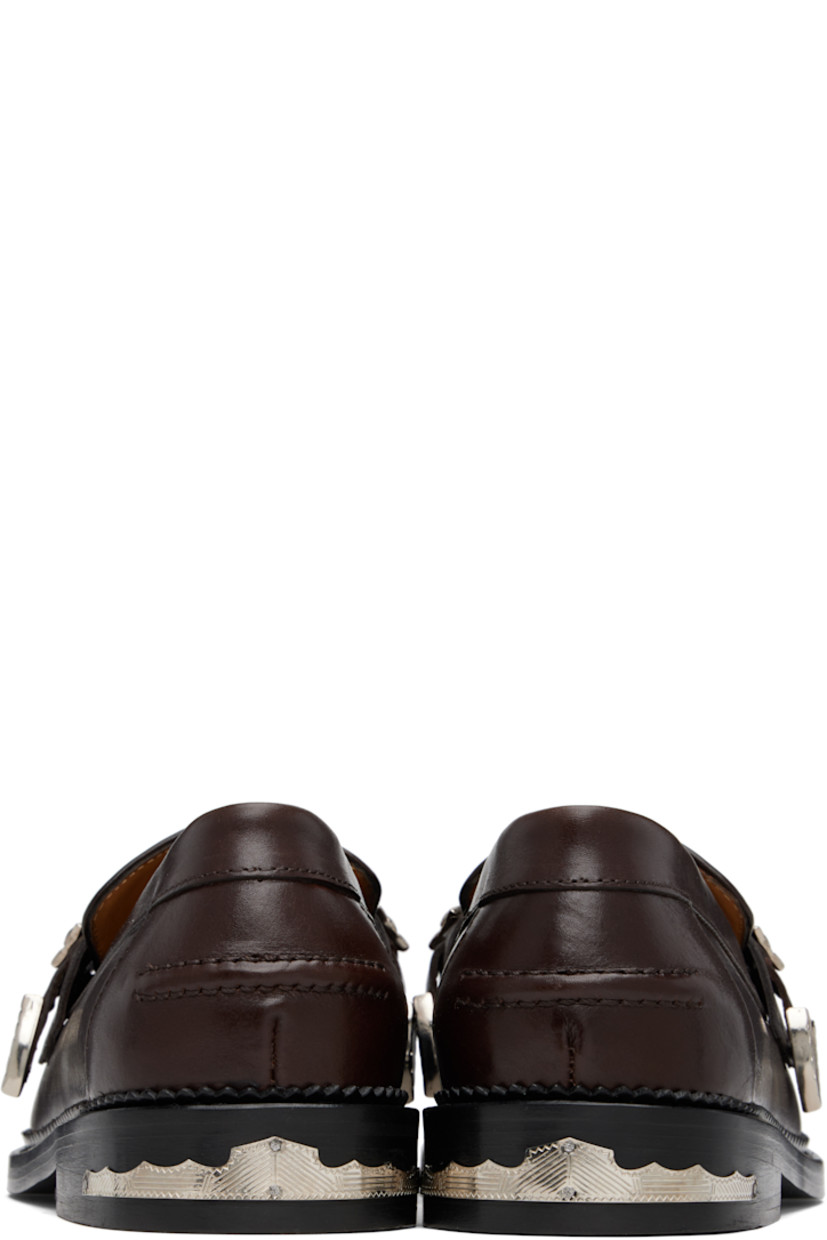 Buffed leather loafers.

· Moc toe
· Strap with graphic hardware at vamp
· Pinched seam at heel counter
· Serrated edge at welt
· Engraved plaque at heel
· Stacked leather heel with rubber injection
· Leather sole

Available exclusively at SSENSE.

Supplier color: Dark brown