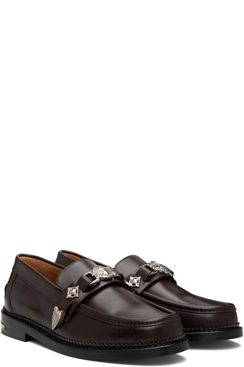 Buffed leather loafers.

· Moc toe
· Strap with graphic hardware at vamp
· Pinched seam at heel counter
· Serrated edge at welt
· Engraved plaque at heel
· Stacked leather heel with rubber injection
· Leather sole

Available exclusively at SSENSE.

Supplier color: Dark brown