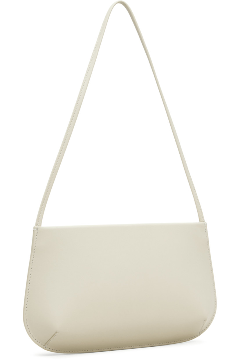 Buffed calfskin shoulder bag.

· Fixed shoulder strap
· Darts at base
· Magnetic closure
· Patch pocket at interior
· Twill lining
· H6" x W11" x D2.25"

Supplier color: Tofu calf