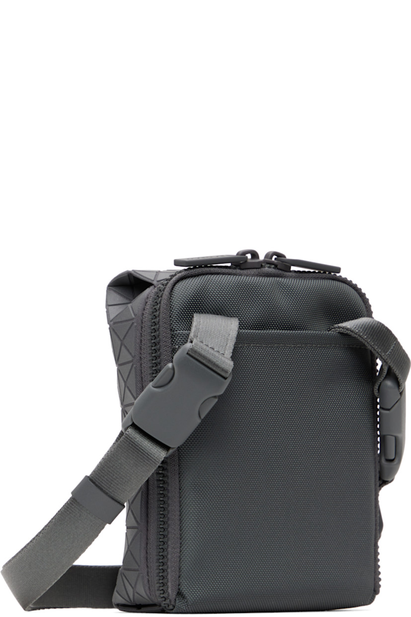 Twill messenger bag in gray.

· Triangular polymer appliqués throughout
· Adjustable and detachable crossbody strap
· Patch pocket at back face
· Two-way zip closure
· Clasp at two-compartment interior
· Zip pocket and three card slots
· H6" x W5" x D2"

Supplier color: One-tone gray
