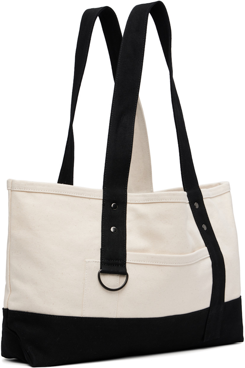 Cotton canvas tote.

· Fixed twin shoulder straps
· D-ring at face
· Patch pocket at face and back face
· Press-stud closure
· Bottle sleeve at interior
· Unlined
· H9.5" x W18" x D4"

Supplier color: Off white