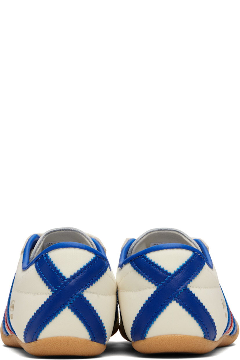 Low-top canvas, buffed leather, and suede sneakers.

· Lace-up closure
· Logo bonded at padded tongue
· Padded collar
· Signature serrated stripes at sides and heel
· Logo stamp at outer side
· Buffed faux-leather and mesh lining
· Textured rubber sole

Supplier color: Cream white/Royal blue/Gum