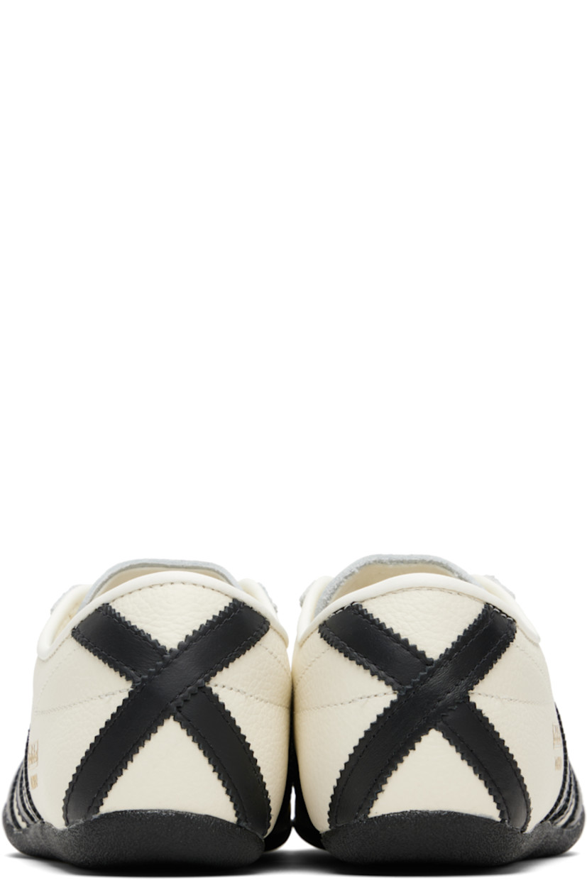 Low-top grained leather sneakers.

· Lace-up closure
· Logo stamp at tongue and outer side
· Padded collar
· Signature serrated stripes at sides and heel
· Mesh lining
· Crêpe-rubber sole

Supplier color: Off white/Core black/Gold metallic