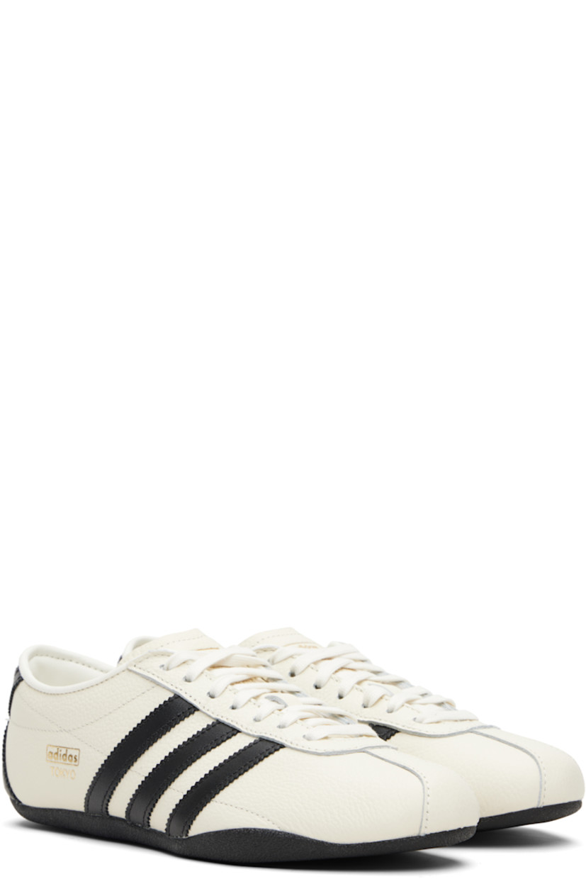 Low-top grained leather sneakers.

· Lace-up closure
· Logo stamp at tongue and outer side
· Padded collar
· Signature serrated stripes at sides and heel
· Mesh lining
· Crêpe-rubber sole

Supplier color: Off white/Core black/Gold metallic