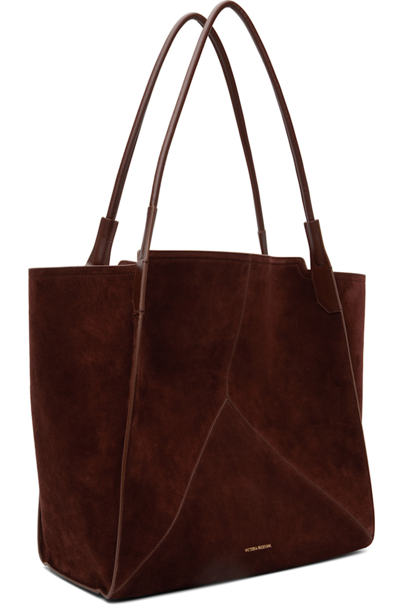Calfskin suede tote.

· Twin rolled shoulder straps
· Logo stamp at face
· Bumper pads at base
· Patch pocket at interior 
· H15.5" x W15" x D7"

Supplier color: Dark brown